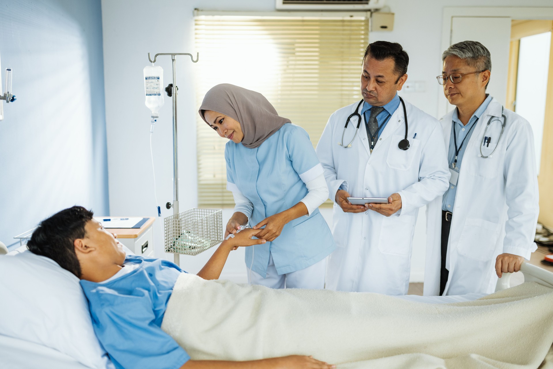 Nurse and doctors preparing young patient for surgery in modern hospital. Young teenager lying in hopsital bed